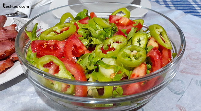 Салат с преобладанием сладкого перца разных сортов на фоне помидоров и огурцов